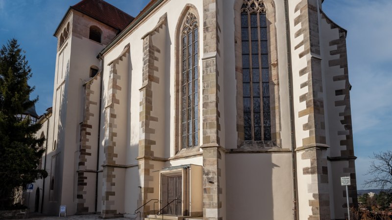 The Backnang collegiate church with its Gothic windows and red roof, surrounded by a paved square, under a clear blue sky., &copy; Ren&eacute; Straube