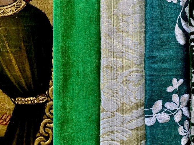 Grüne Stoffe in verschiedenen Texturen neben einem Gemälde mit goldenen Details und einem dunkelgrünen Gewand., © Landesmuseum Württemberg