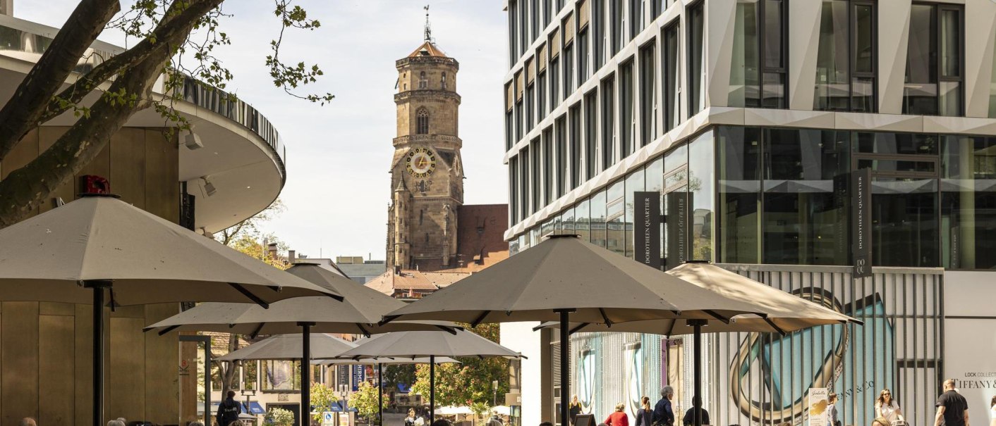 Das Dorotheenquartier in Stuttgart mit modernen Gebäuden, Sonnenschirmen und der historischen Stiftskirche im Hintergrund., © Stuttgart-Marketing GmbH, Sarah Schmid