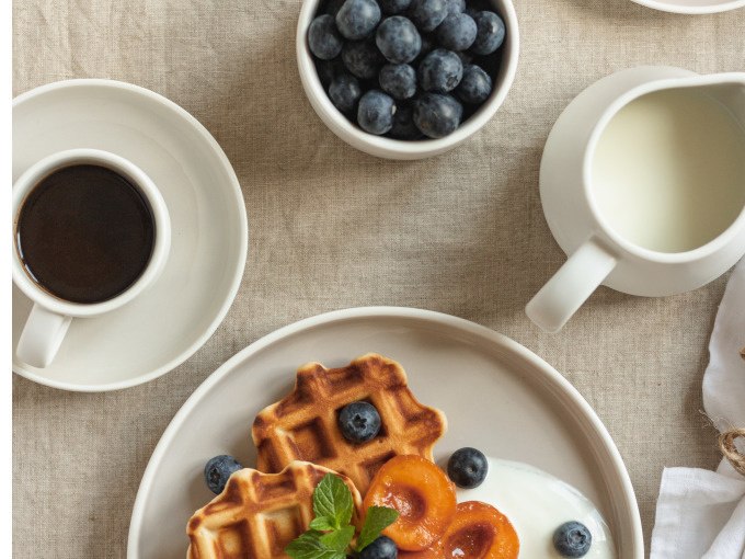 Waffeln mit Blaubeeren, Aprikosen und Joghurt auf einem Teller, daneben Kaffee und Milch auf einem Tisch., © Cool-Tours StattReisen Waffeln mit Blaubeeren, Aprikosen und Joghurt auf einem Teller, daneben Kaffee und Milch auf einem Tisch., © Cool-Tours StattReisen