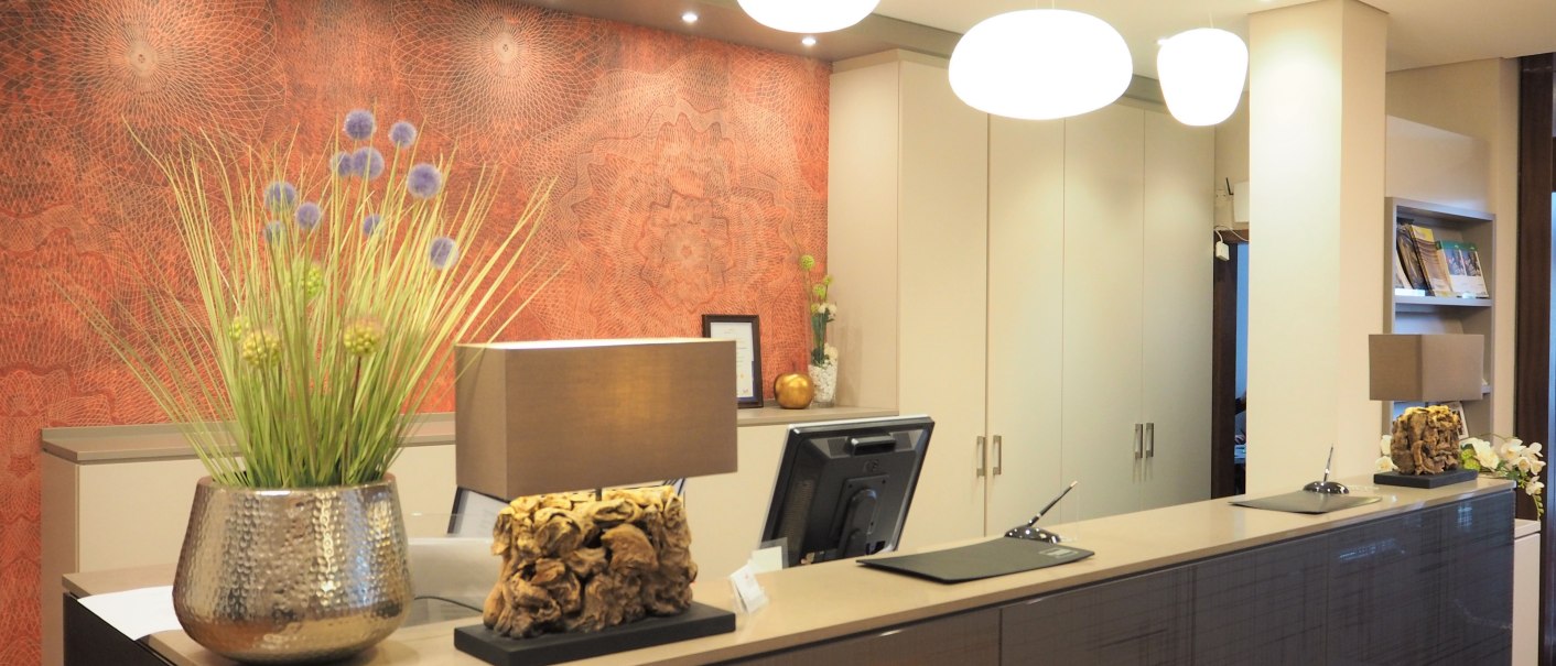 Modern reception with stylish decoration, plants and lighting. The wall has an artistic pattern and there is a computer on the counter., © Hotel Fuchsen Modern reception with stylish decoration, plants and lighting. The wall has an artistic pattern and there is a computer on the counter., © Hotel Fuchsen