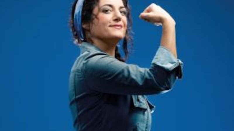 Woman in work clothes with headscarf shows a strong pose against a blue background, inspired by Rosie the Riveter., &copy; Altes Schauspielhaus und Kom&ouml;die im Marquardt e.V.