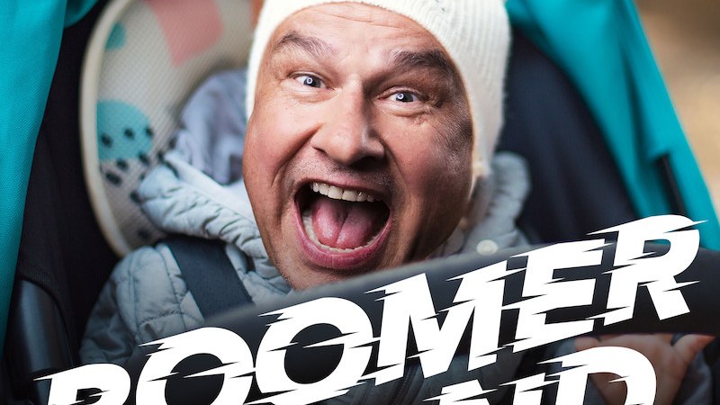 Ein Mann mit wei&szlig;er M&uuml;tze lacht fr&ouml;hlich in die Kamera. Der Schriftzug 'Boomer Land' ist gro&szlig; im Vordergrund zu sehen., &copy; Theaterhaus Stuttgart e.V.