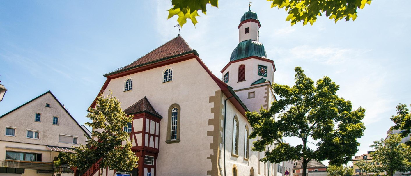 A church in the old town of Winnenden, surrounded by trees and bright sunshine. The sky is clear and blue., © Stuttgart-Marketing GmbH, Sarah Schmid