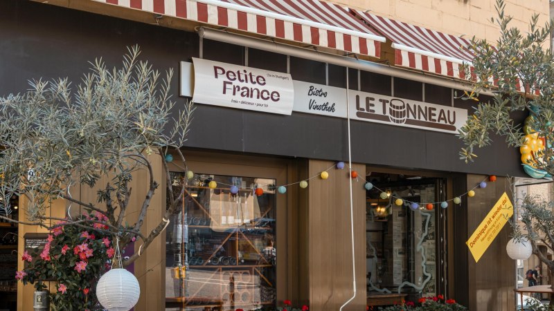 Bistro 'Petite France' und 'Le Tonneau' mit rot-weiß gestreifter Markise, bunten Lichtern und Pflanzen dekoriert. Einladende Atmosphäre., © SMG, Sarah Schmid