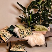 Ein Sofa mit bunten Kissen und einem weißen Fell, umgeben von großen grünen Zimmerpflanzen., © Merz & Benzing GmbH Ein Sofa mit bunten Kissen und einem weißen Fell, umgeben von großen grünen Zimmerpflanzen., © Merz & Benzing GmbH