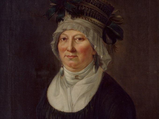 Historisches Portr&auml;t einer Frau in traditioneller Kleidung mit aufwendiger Kopfbedeckung und Ohrringen, vor einem dunklen Hintergrund., &copy; Landesmuseum W&uuml;rttemberg