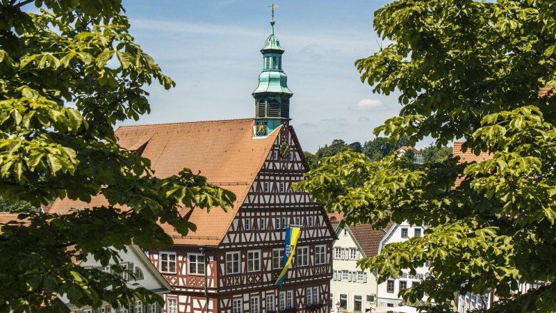 Backnang's half-timbered town hall stands out against the backdrop of green trees. The tower, with its clock and weather vane, is clearly visible., &copy; SMG Stuttgart Marketing GmbH - Sarah Schmid