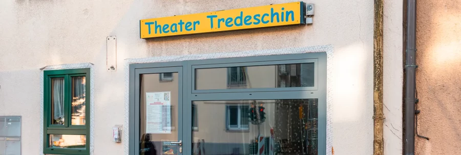 The entrance to the Tredeschin Theater, with a yellow sign above the door. A window with a curtain and a small display case are visible., © SMG, Sarah Schmid The entrance to the Tredeschin Theater, with a yellow sign above the door. A window with a curtain and a small display case are visible., © SMG, Sarah Schmid
