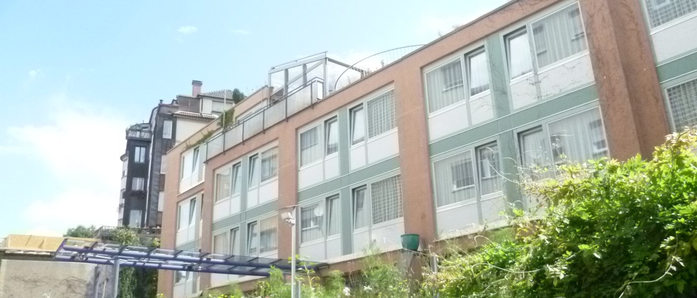 Mehrstöckiges Gebäude mit großen Fenstern, umgeben von Pflanzen. Ein Schild weist auf einen Parkplatz für Hotel Abalon hin., © Abalon Hotel Ideal Mehrstöckiges Gebäude mit großen Fenstern, umgeben von Pflanzen. Ein Schild weist auf einen Parkplatz für Hotel Abalon hin., © Abalon Hotel Ideal