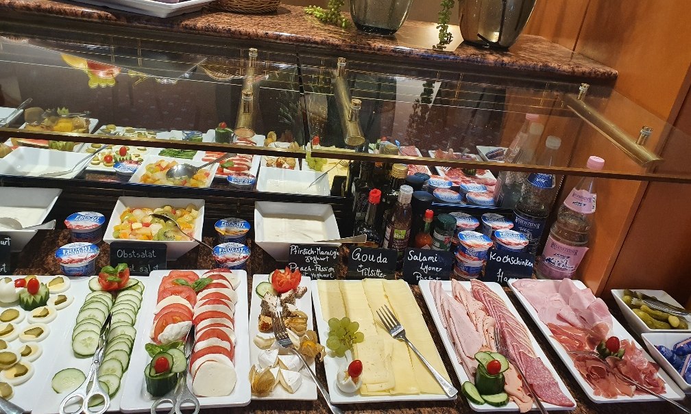 Ein reichhaltiges Frühstücksbuffet mit Obst, Käse, Aufschnitt, Joghurt und Getränken, dekoriert mit frischen Kräutern., © PLAZA INN Rieker Stuttgart Hauptbahnhof Ein reichhaltiges Frühstücksbuffet mit Obst, Käse, Aufschnitt, Joghurt und Getränken, dekoriert mit frischen Kräutern., © PLAZA INN Rieker Stuttgart Hauptbahnhof