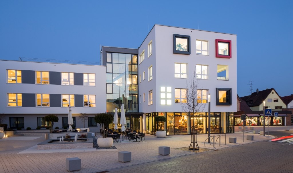 Modern hotel building at dusk, illuminated windows, terrace with parasols, clean lines and geometric shapes., © Hotel LOGIS Modern hotel building at dusk, illuminated windows, terrace with parasols, clean lines and geometric shapes., © Hotel LOGIS