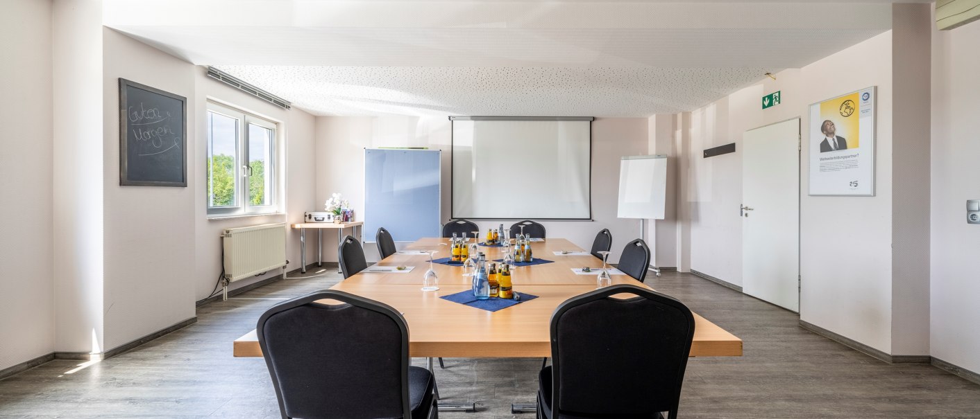 Meeting room with large table, chairs, drinks and presentation equipment. Windows let in daylight and a 'Good morning' board hangs on the wall., © Plaza INN Stuttgart-Filderstadt Meeting room with large table, chairs, drinks and presentation equipment. Windows let in daylight and a 'Good morning' board hangs on the wall., © Plaza INN Stuttgart-Filderstadt