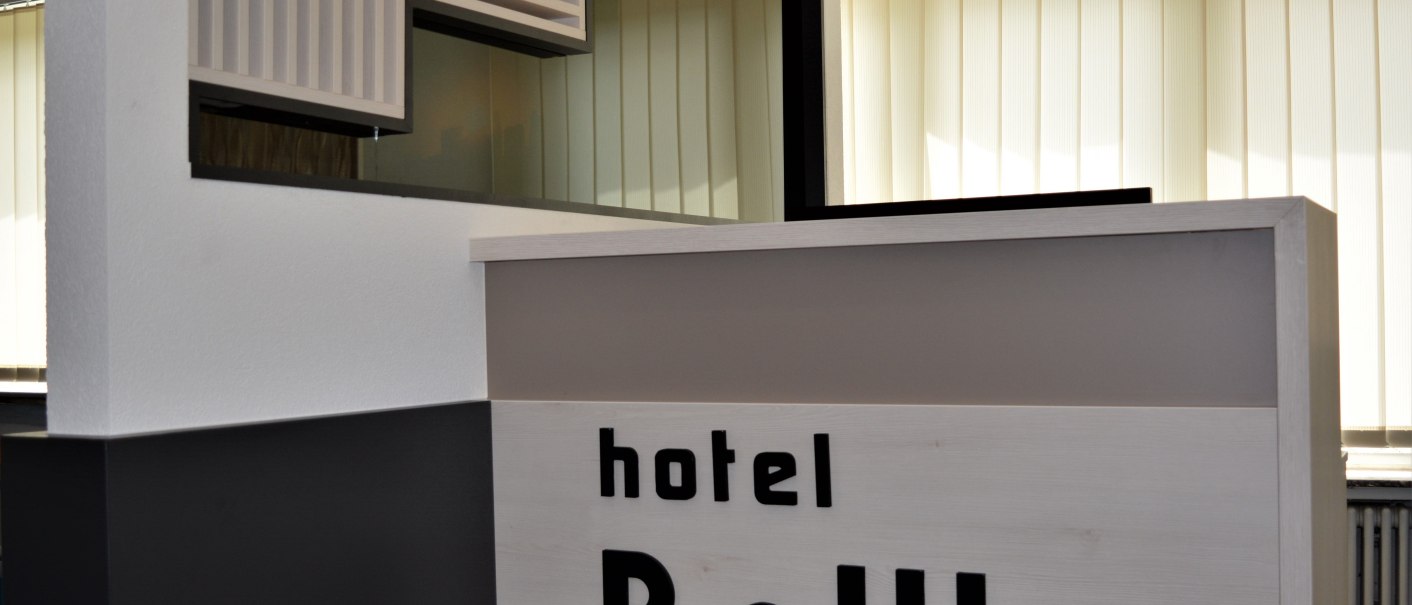 Moderner Rezeptionstresen im Hotel BaWu mit hellem Holz und stilvollem Design. Im Hintergrund sind vertikale Jalousien zu sehen., © Hotel BaWü Moderner Rezeptionstresen im Hotel BaWu mit hellem Holz und stilvollem Design. Im Hintergrund sind vertikale Jalousien zu sehen., © Hotel BaWü