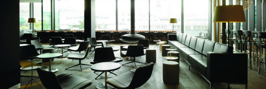 Moderne Lounge mit schwarzen Ledersesseln, Tischen und Stehlampen. Gro&szlig;e Fenster bieten Blick nach drau&szlig;en. Elegantes, minimalistisches Design., &copy; karls kitchen, Stuttgart