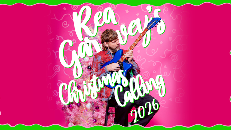 Ein Mann spielt Gitarre vor einem pinken Hintergrund mit Weihnachtsbaum. Der Text "Rea Garvey's Christmas Calling 2026" ist prominent zu sehen., &copy; links im Bild