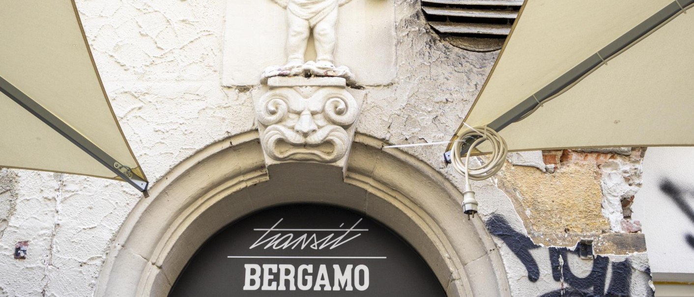 Stone figure above an archway with the inscription 'transit BERGAMO'. Graffiti and weathered wall in the background., &copy; SMG, Sarah Schmid
