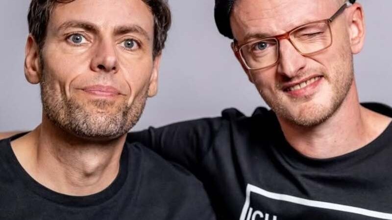 Zwei Männer in schwarzen T-Shirts, einer trägt eine Mütze und zwinkert. Sie posieren vor einem neutralen Hintergrund., © Rosenau Kultur e.V. Zwei Männer in schwarzen T-Shirts, einer trägt eine Mütze und zwinkert. Sie posieren vor einem neutralen Hintergrund., © Rosenau Kultur e.V.