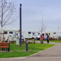Wohnmobilstellplatz mit mehreren Wohnmobilen, kahlen Bäumen und einer Bank. Zwei Personen stehen auf dem Weg. Trübes Wetter., © Panorama Therme Beuren, Birgit Eschment
