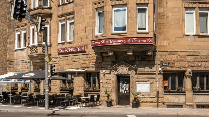 Historisches Geb&auml;ude mit Restaurant Taverna Yol, Sitzpl&auml;tze im Freien, Stra&szlig;enschilder und Ampeln. Sonniger Tag, Blumen in Fenstern., &copy; SMG, Sarah Schmid