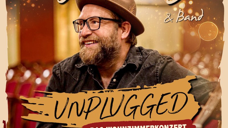 Gregor Meyle on an album cover with hat and glasses, smiling in a concert hall. Text: 'Unplugged - The living room concert'., &copy; C2 Concerts GmbH