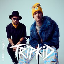 Zwei Männer posieren modisch, einer trägt eine gelbe Mütze und blaue Jacke, der andere einen Hut. Der Schriftzug 'TRIPKID' ist prominent zu sehen., © links im Bild