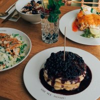 A table with salad, pancakes with berries, a drink and other dishes on a wooden table., &copy; The Gardeners Nosh, Stuttgart