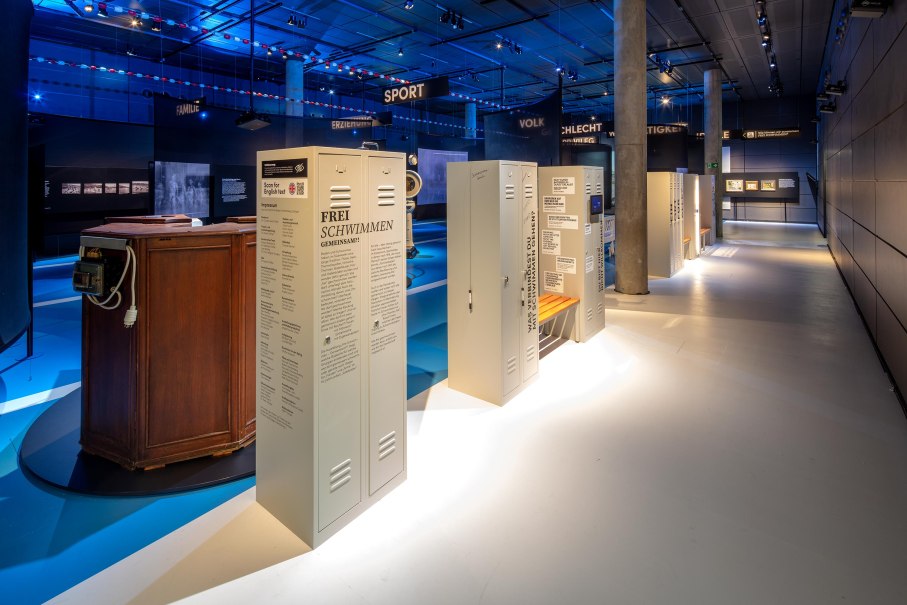 Ausstellung 'Frei Schwimmen' im Haus der Geschichte Baden-Württemberg mit beleuchteten Schließfächern und blauer Atmosphäre., © HdGBW/ Daniel Stauch