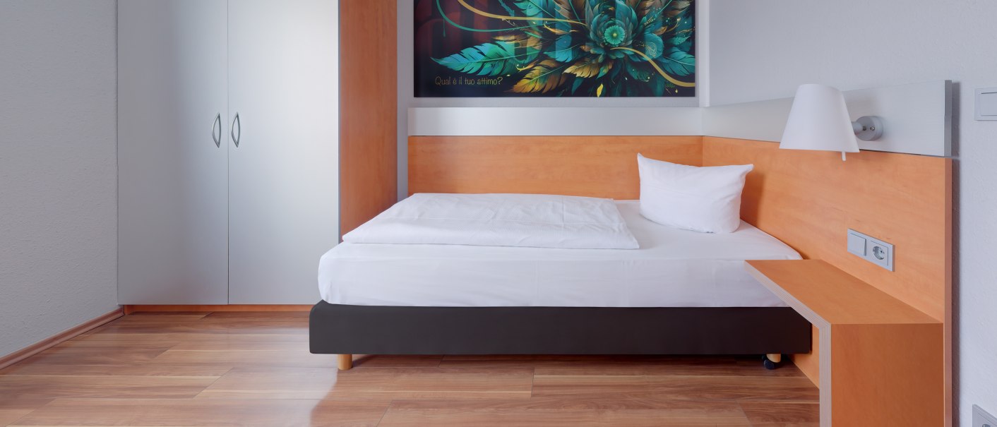 Ein modernes Einzelzimmer mit Holzboden, einem Bett, einem Schrank und einem Kunstwerk an der Wand., © attimo Hotel Stuttgart Ein modernes Einzelzimmer mit Holzboden, einem Bett, einem Schrank und einem Kunstwerk an der Wand., © attimo Hotel Stuttgart