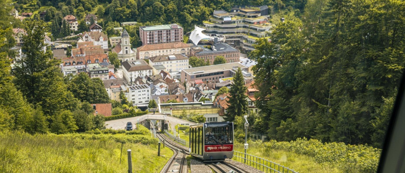 The Sommerbergbahn in Bad Wildbad runs through a green landscape with a view of the town in the background., &copy; Stuttgart-Marketing GmbH, Sarah Schmid