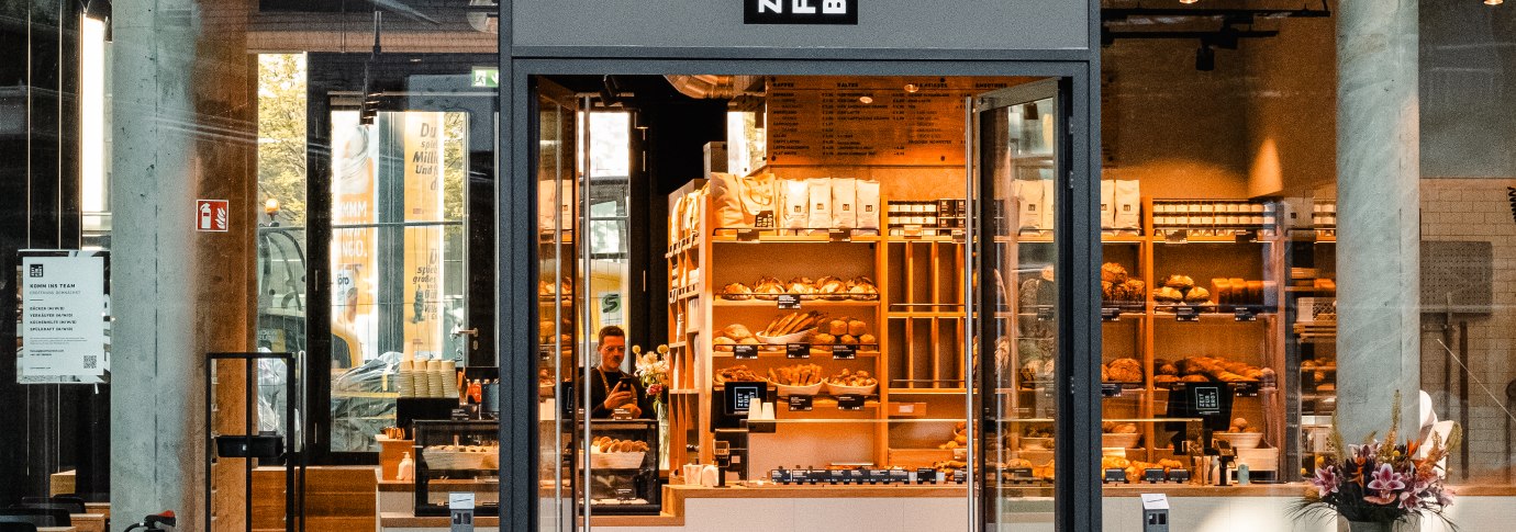 Eingang einer B&auml;ckerei mit Glasfront. Im Inneren sind Regale mit Backwaren zu sehen. &Uuml;ber der T&uuml;r steht 'Zeit f&uuml;r Brot'., &copy; Zeit f&uuml;r Brot Stuttgart