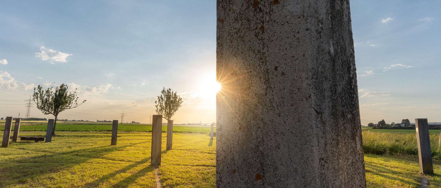 Sunset in the Triangulation garden in Kornwestheim. Concrete pillars and trees on a meadow, the sun shines through between the pillars., © Stuttgart-Marketing GmbH, Martina Denker