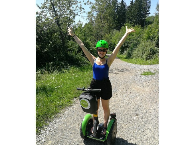 Eine Person mit Helm und Sonnenbrille steht auf einem Segway auf einem Schotterweg, umgeben von Bäumen und Pflanzen., © Cool-Tours StattReisen Eine Person mit Helm und Sonnenbrille steht auf einem Segway auf einem Schotterweg, umgeben von Bäumen und Pflanzen., © Cool-Tours StattReisen