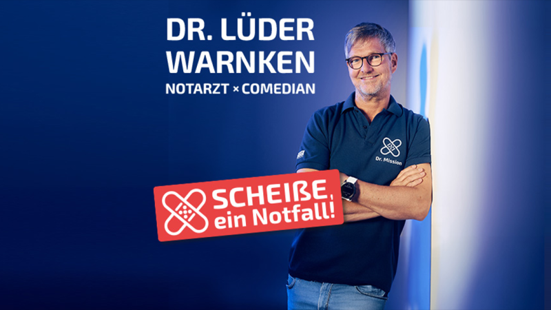 Ein Mann in einem blauen Polohemd steht l&auml;chelnd vor einem blauen Hintergrund. Text: Dr. L&uuml;der Warnken, Notarzt und Comedian. Ein rotes Schild zeigt 'Schei&szlig;e, ein Notfall!'., &copy; links im Bild