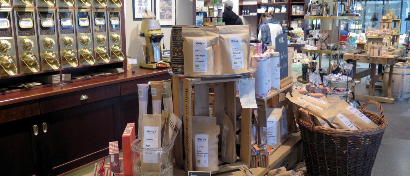Verkaufsraum einer Kaffeerösterei mit goldenen Kaffeespendern, Kaffeetüten und verschiedenen Produkten auf Holztischen und Regalen., © Stuttgart-Marketing GmbH, Lara Seeger