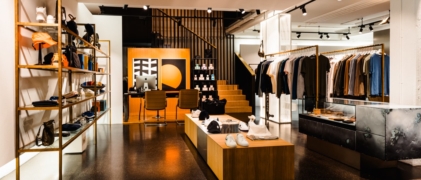 Modernes Herrenbekleidungsgesch&auml;ft mit stilvoller Einrichtung, Regalen voller Kleidung und Accessoires. Einladende Atmosph&auml;re mit warmem Licht., &copy; Bungalow