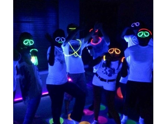 Gruppe von Menschen mit leuchtenden Brillen und Halsketten in einem dunklen Raum, die unter Schwarzlicht strahlen., © Cool-Tours StattReisen Gruppe von Menschen mit leuchtenden Brillen und Halsketten in einem dunklen Raum, die unter Schwarzlicht strahlen., © Cool-Tours StattReisen