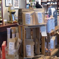 Sales room of a coffee roastery with golden coffee dispensers, coffee bags and various products on wooden tables and shelves., &copy; &copy; Stuttgart-Marketing GmbH, Lara Seeger