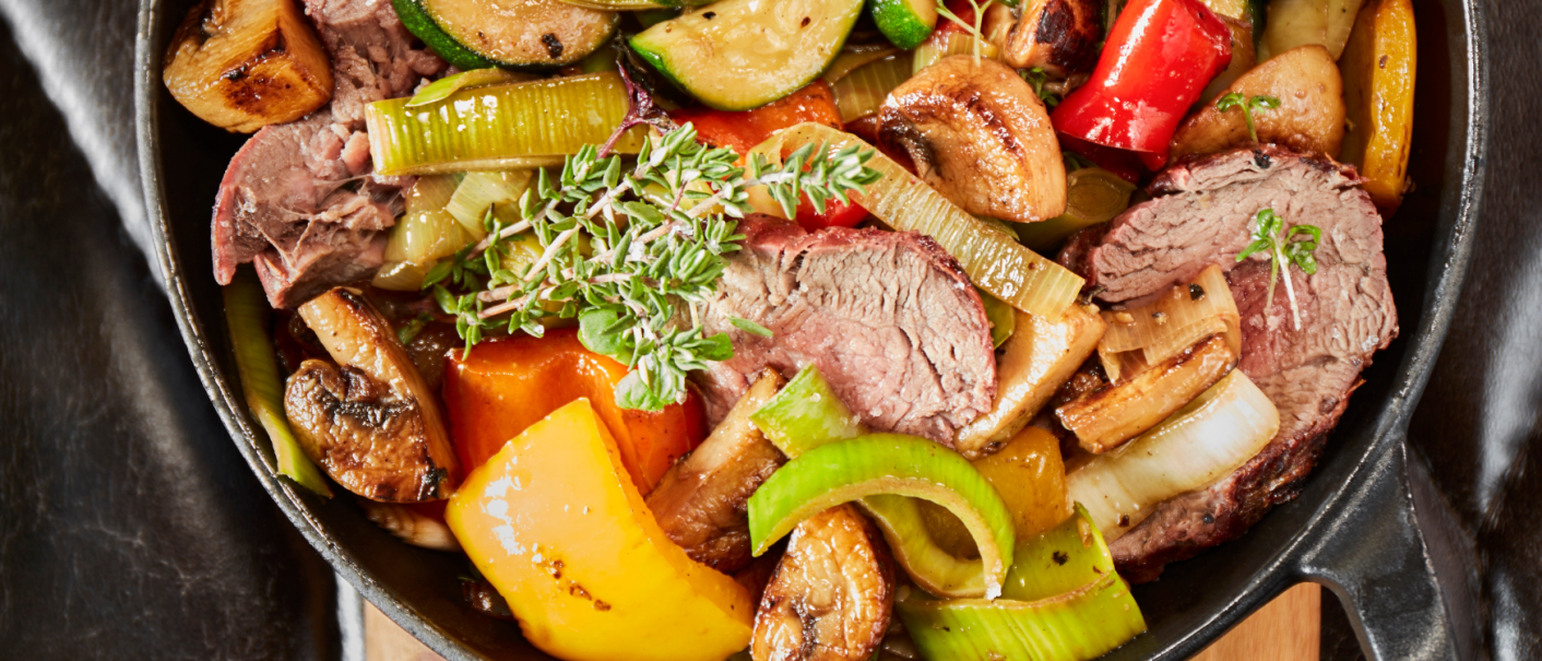 Pan with roasted meat, zucchini, peppers, mushrooms and herbs, served on a wooden board., © MAREDO
