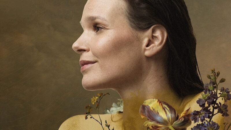 Ein Portr&auml;t einer Frau mit nassen Haaren, umgeben von bunten Blumen vor einem goldenen Hintergrund. Oben links steht "Susan Wolf Gold"., &copy; Mag. Susanne Maierhofer