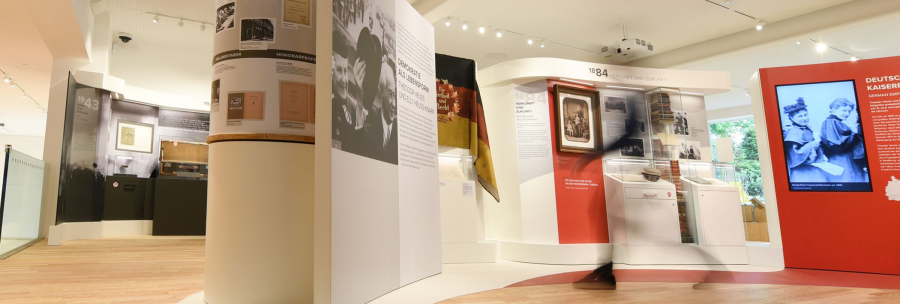 Interior view of the Theodor Heuss House in Stuttgart with exhibits, information boards and a German flag., © Stiftung Bundespräsident Theodor-Heuss-Haus / Franziska Kraufmann