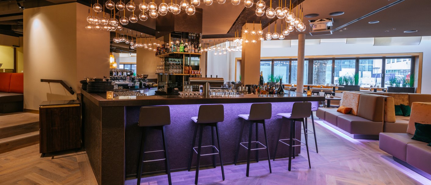 Modern bar with stylish lighting, high stools and cozy seating areas. The atmosphere is inviting and elegant., &copy; Breuninger