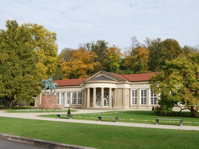 Historic building in the Bad Cannstatt spa gardens with equestrian statue and autumnal tree backdrop., &copy; Cool-Tours StattReisen