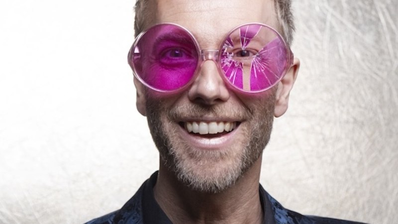Ein Mann tr&auml;gt eine gro&szlig;e, pinke Brille und ein blau gemustertes Jackett vor einem hellen Hintergrund., &copy; Renitenztheater Stuttgart e.V.