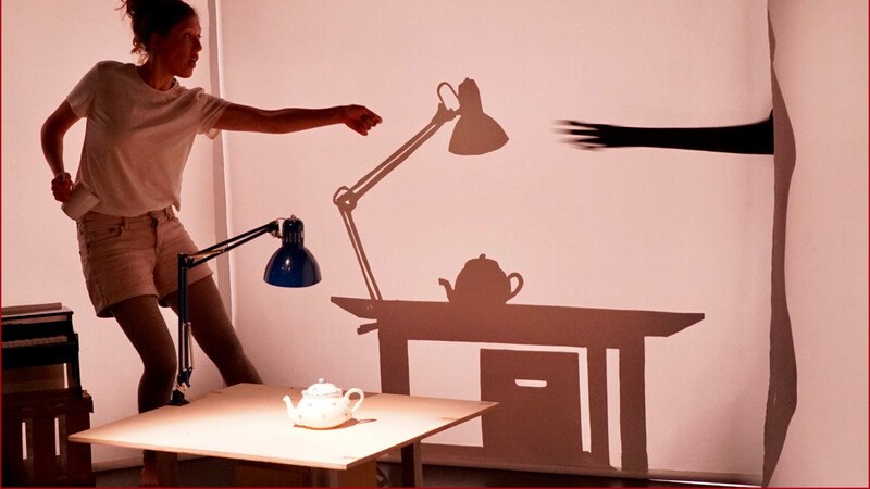 Eine Frau posiert vor einer Wand, ihre Schatten formen eine Lampe und einen Tisch mit Teekanne., © FITZ Das Theater animierter Formen