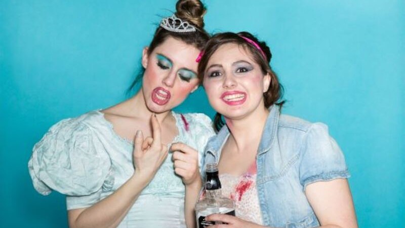 Zwei Frauen mit auff&auml;lligem Make-up und Kost&uuml;men posieren vor einem blauen Hintergrund. Eine h&auml;lt eine Flasche, beide wirken ausgelassen., &copy; Renitenztheater Stuttgart e.V.