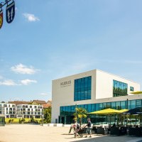 Modern market square in Remseck with the 'KUBUS' building, a maypole with a coat of arms and people out for a walk. Sunny day with blue sky., © Stuttgart-Marketing GmbH, Sarah Schmid Modern market square in Remseck with the 'KUBUS' building, a maypole with a coat of arms and people out for a walk. Sunny day with blue sky., © Stuttgart-Marketing GmbH, Sarah Schmid