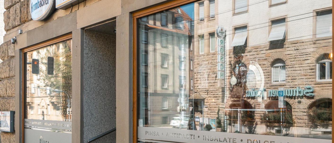 Exterior view of a restaurant with the inscription 'Pinsa Manufaktur' and reflection of buildings in the window., © SMG Stuttgart Marketing GmbH - Sarah Schmid Exterior view of a restaurant with the inscription 'Pinsa Manufaktur' and reflection of buildings in the window., © SMG Stuttgart Marketing GmbH - Sarah Schmid