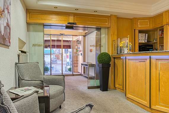 Reception area with wooden furniture, seating and glass door. Inviting atmosphere with plants and decoration., © Centro Hotels