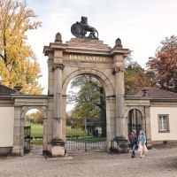 Historic gate with 'Rosenstein' lettering, flanked by buildings. Autumnal trees in the background, two people walking., © TMBW, Christoph Düpper